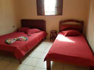马里利亚Hotel Nove De Julho的一间卧室设有两张带红色床单的床和窗户。