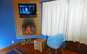 维奥康德马奥Pousada Portal Dos Ventos的客厅设有壁炉、电视和椅子