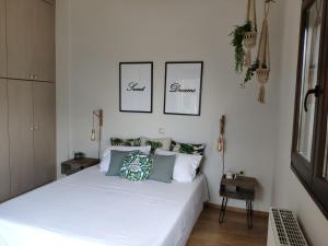 尼亚普拉莫斯Olive Tree Cottage 2的卧室配有一张白色床,墙上挂有两张照片