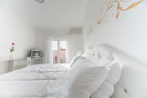 萨武德里亚Hotel La Settima Luna的白色的卧室设有白色的床和窗户。