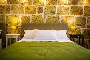 阿沃拉Regina Elena Rooms的一间卧室设有绿色的床和石墙