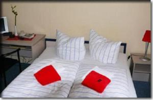米罗梅克伦堡霍夫酒店的一张带两个红色枕头的白色床