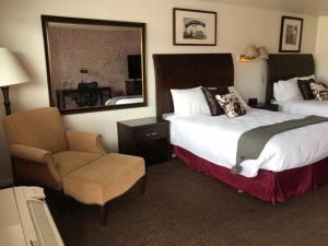 罗克斯普林Country West Motel of Rock Springs的酒店客房带两张床、椅子和镜子