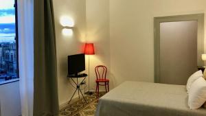 鲁蒂利亚诺Dimora Essenza的一间卧室配有一张床、一台电视和一把椅子