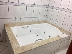 卡内拉Hotel Carpevita的白色瓷砖浴室内的白色浴缸