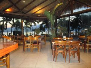 伊利亚贝拉Ilha Flat Hotel Suíte Bella - 4207 - Ilhabela的一间设有木桌和椅子的餐厅,享有海景