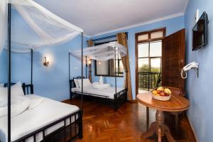 阿鲁沙Mrimba Palm Hotel的一间卧室设有两张床和一张带一碗水果的桌子。