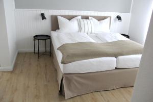 诺德代希Strandhuus Norddeich的卧室配有一张带白色床单和枕头的大床。