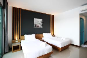 普吉镇The Malika Hotel - SHA Extra Plus的一间卧室配有两张带白色床单的床