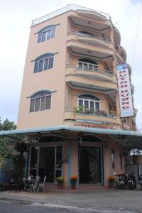 河仙Huỳnh Hương Guesthouse的一座高大的建筑,前面有一间餐厅