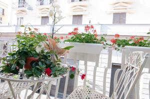 那不勒斯Relais Bijoux Napoli的阳台配有白色椅子,种有鲜花和植物