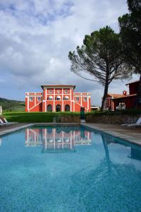 卡帕尔比奥法托丽亚利瓜帝欧雷别墅酒店的一座红色的建筑,前面有一个游泳池