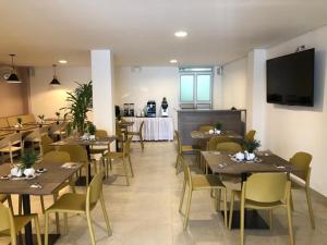 图马科Colon Plaza Hotel的餐厅设有木桌、椅子和电视