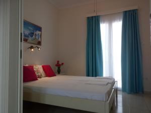 帕罗奇亚梅莱蒂斯公寓酒店的一间卧室配有一张带蓝色窗帘的床和一扇窗户
