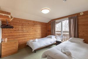 二世古North Point的配有木墙和窗户的客房内的两张床