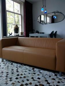 阿姆斯特丹Jordaan Canal View Apartment的客厅里设有一张棕色沙发,配有窗户