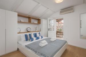 杜布罗夫尼克奥拉夫公寓的白色卧室配有一张带蓝色枕头的大床