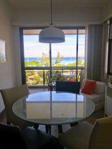 里约热内卢Marbella Apart Hotel的客厅设有玻璃桌,享有海景