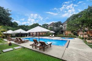 沙努尔Villa Pantai Karang的庭院内带椅子和遮阳伞的游泳池