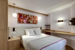 巴黎亚历山大歌剧院酒店的酒店客房设有一张床,墙上挂有绘画作品