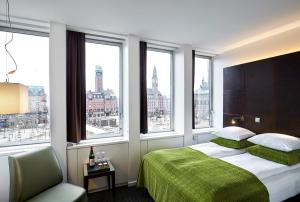 哥本哈根广场酒店的一间卧室配有一张带绿毯的床和窗户。