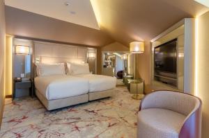 里斯本TURIM Boulevard Hotel的一间卧室配有一张床、两把椅子和电视