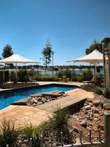 奥古斯塔港雄伟绿洲公寓的一个带遮阳伞和椅子的游泳池和一个庭院