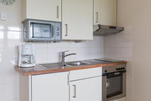 库克斯港Strandhaus Christiansen的厨房配有白色橱柜、水槽和微波炉