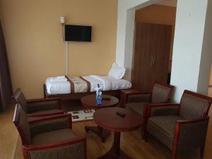 NarokEsikar Gardens Hotel的酒店客房带一张床、一张桌子和椅子