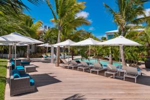 格雷斯湾The Oasis at Grace Bay的度假酒店的游泳池配有椅子和遮阳伞