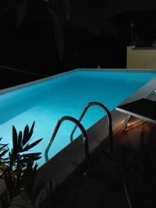 GuardialfieraB&B Il Belvedere的夜晚带桌子的蓝色游泳池