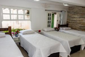 帕赖索波利斯Pousada Paraiso do Alto的带3张白色床单的床的房间