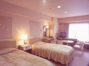 高知土佐御苑酒店的酒店客房设有两张床、一张桌子和一台电视。