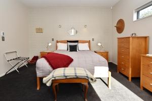 基督城The Apartment Within - Christchurch Holiday Homes的一间卧室配有一张大床和一把椅子