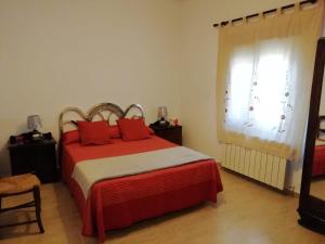 Navas de EstenaCasa Simona的一间卧室配有一张带红色枕头的床和一扇窗户