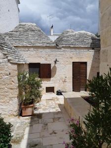 阿尔贝罗贝洛Alberobello Casa Vacanze - Pathos tra i Trulli的一座古老的石头建筑,有门和一些植物