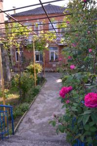 库塔伊西Friends House的一座花园,花园内种植着粉红色玫瑰,并拥有一座砖砌房屋