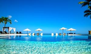 喀巴里特维林罗海滩公寓式度假酒店的海滩上带椅子和遮阳伞的游泳池