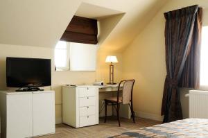 伊赫特赫姆沙龙德韦德酒店的一间卧室配有一张桌子、一台电视和一张床