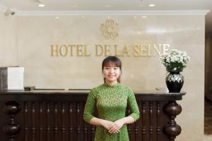 河内Hotel De La Seine的站在酒店delia标志前身的绿色女装