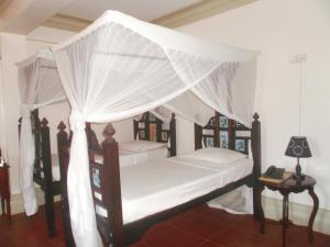 桑给巴尔阿斯米尼宫酒店的一间卧室配有两张带蚊帐的床