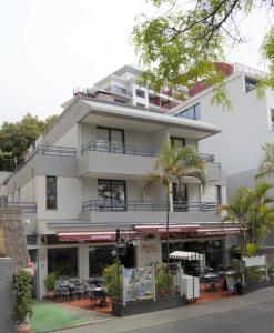 丰沙尔Apartamentos Turísticos Vitoria by Petit Hotels的前面有桌椅的白色建筑
