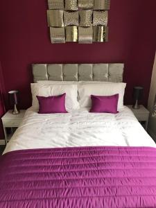 切姆The Avenues的一张带紫色床单和两个紫色枕头的白色床