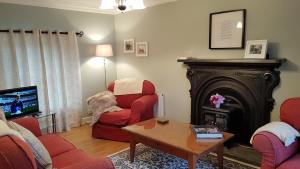 利斯坎诺Bay View House的客厅设有壁炉和红色椅子