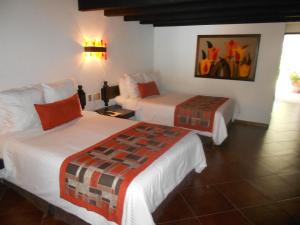 圣米格尔-德阿连德Hotel Hacienda Taboada (Aguas Termales)的酒店客房设有两张床,墙上挂有绘画作品