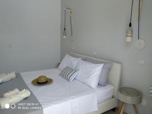 帕莱欧卡斯提撒Studios Paleokastritsa - Sun's Gift的一张带白色枕头的床和一顶帽子