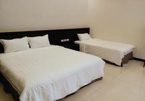 台东真善居民宿的客房内的两张床和白色床单