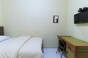 沙马林达Guest House Samarinda的一间卧室配有一张床、一张书桌和一台电视