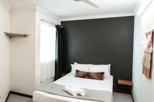 凯恩斯诺玛德汽车旅馆的卧室配有一张白色的床和黑色的墙壁