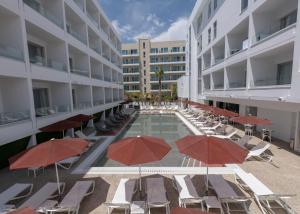 普罗塔拉斯Kokkinos Boutique Hotel的一座带椅子和遮阳伞的游泳池位于一座建筑旁边